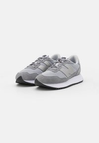 Zapatillas deportivas grises con parte superior de malla y ante, puntera redondeada, sistema de cordones, media suela acolchada y suela exterior negra en contraste.