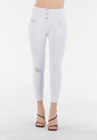 Jeans bianchi a vita alta in tessuto elasticizzato, con chiusura a bottone, tasche anteriori e strappo sul ginocchio destro.