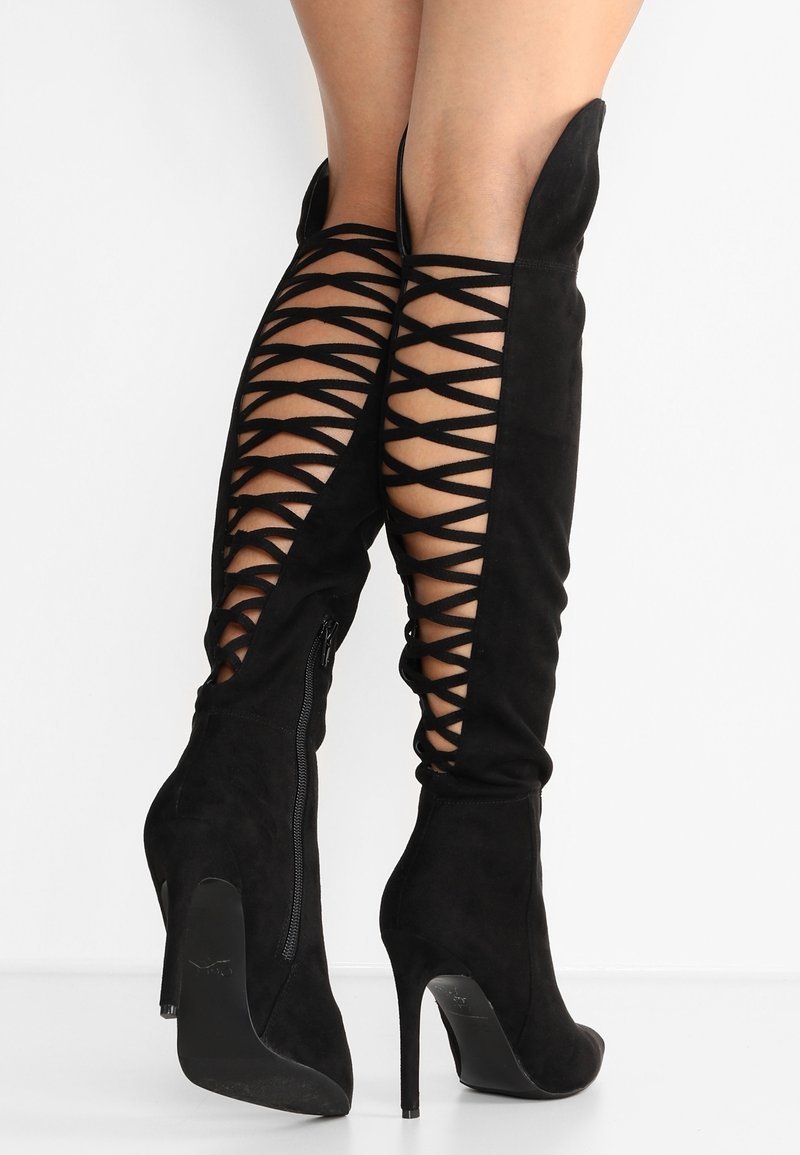 Black suede thigh-high boots with a stiletto heel, featuring an open lattice design along the sides and a zip closure on the inner ankle.