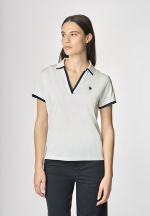Polo bianco con rifiniture blu navy, maniche corte, scollatura a V e un piccolo logo ricamato sul petto. Materiale in cotone liscio.