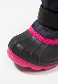 Sort vandtæt støvle med lyserøde accenter, tekstureret gummisål og en polstret nylonoverdel. Har et sikkert sort bånd rundt om anklene.