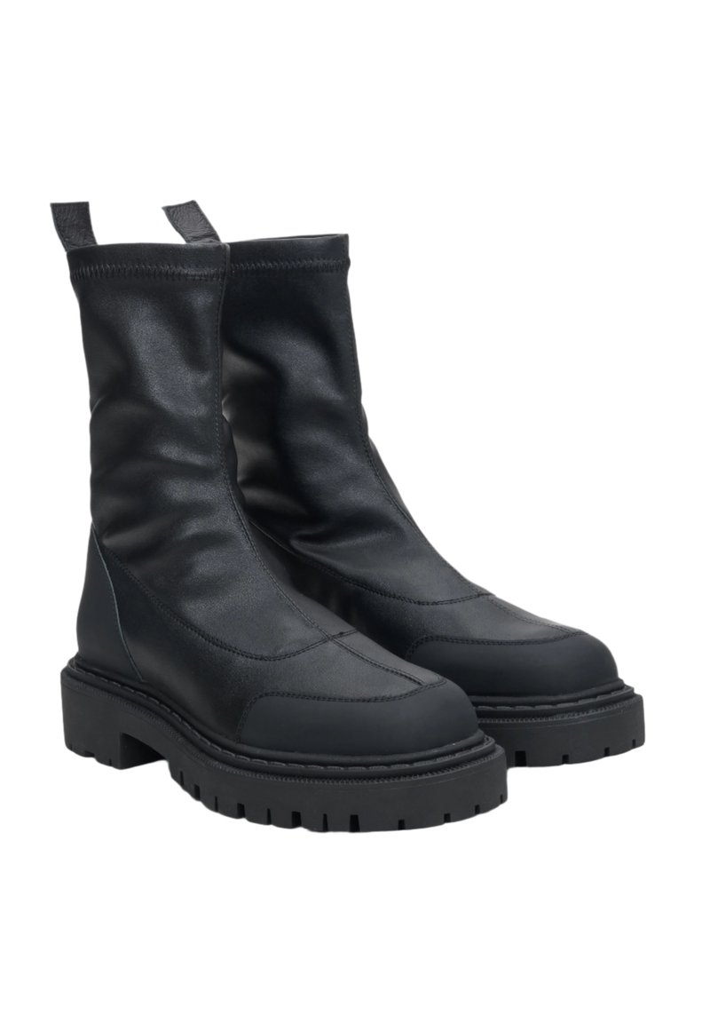 Czarne skórzane botki z luźnym fasonem, grubą gumową podeszwą i widocznymi detalami szwów. Wzmocniona pętla z tyłu dla łatwego zakładania.