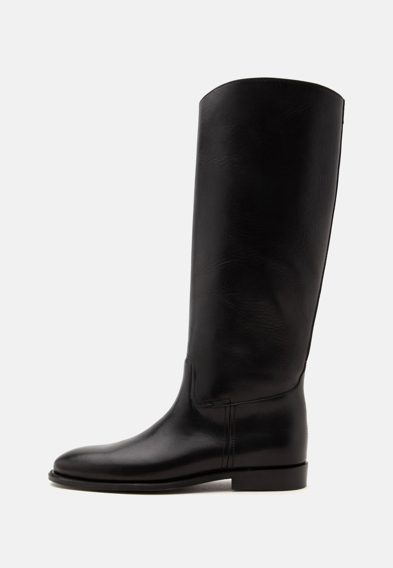 Botte haute en cuir noir avec semelle plate et bout arrondi, vue de côté sur fond clair.
