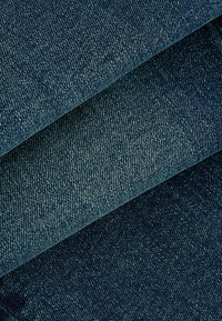 Falde din țesătură denim de un albastru închis, evidențiind o țesătură texturată cu accente de un albastru mai deschis. Finisaj neted, cu un aspect clasic și solid.