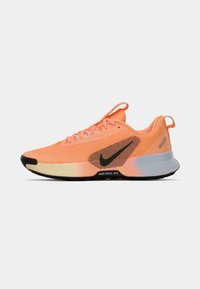 Nike buty biegowe w jasnopomarańczowej siateczkowej cholewce, czarnym logo i beżowej podeszwie środkowej. Zawierają teksturowany obcas i wytrzymałą czarną gumową podeszwę.