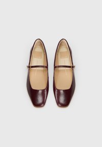 Ballerine in pelle bordeaux con punta quadrata, una fascia stretta con una fibbia dorata e una fodera interna liscia.