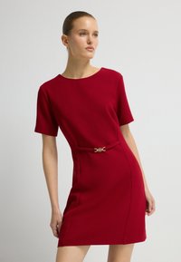 Rood korte mouwen jurk met een ronde halslijn, met een getailleerde taille en een gouden gesp accent, en een op maat gemaakte silhouet.