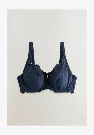 Tumši zils krūšturis ar mežģīņu apmalēm un punktiņu rakstu, aprīkots ar regulējamiem siksniņām un strukturētu, ar stiepli atbalstītu dizainu.