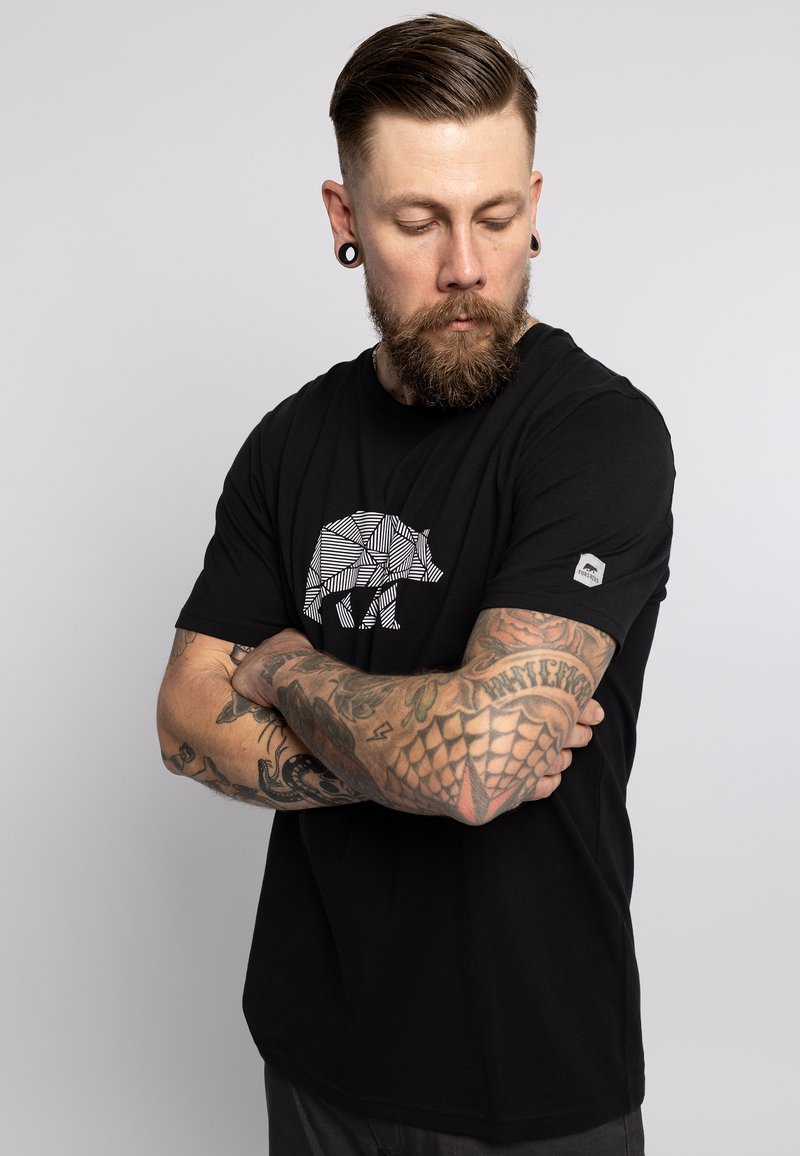 Camiseta negra de algodón con un diseño geométrico de un oso blanco en el frente y un acento decorativo en la manga.