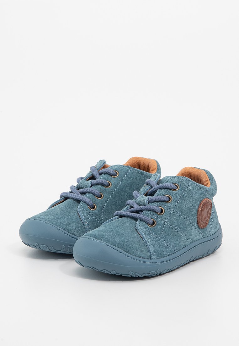 Blaue Wildlederschuhe mit runden Gummizähnen, braunem Lederlogo-Patch und blauen Schnürsenkeln. Das Innere ist mit einem hellbraunen Futter ausgestattet. Niedrig geschnittenes Design.