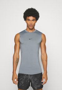 Graues ärmelloses Sportshirt mit rundem Halsausschnitt und schwarzem Nike-Logo, aus einem glatten, leichten Stoff gefertigt.