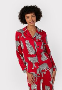 Red satin pajama set featuring black and white leopard patterns, with a button-up top and long sleeves, complemented by matching pants.