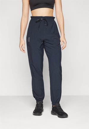 Marineblaue Sporthose mit elastischem Bund und verstellbarem Kordelzug, ausgestattet mit Knöchelabschlüssen und einem Logo-Detail an der Seite.