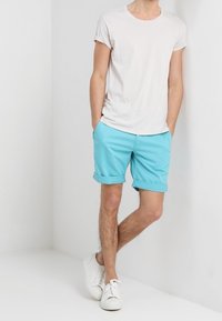 Světle šedé tričko s krátkým rukávem spárované s jasně modrými zkrácenými kalhotami a bílými teniskami, s jednoduchým designem a hladkou texturou.