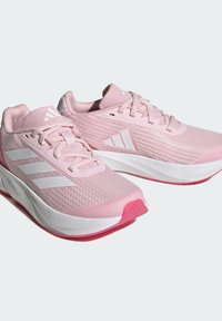 Scarpe da atletica di colore rosa chiaro con tomaia in mesh, dettagli bianchi, suola testurizzata e tre strisce bianche su ogni lato. Design con punta arrotondata.
