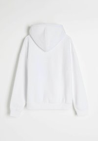 Biała bluza z gładkiego materiału, z regulowanym kapturem na sznurku oraz ściągaczami przy rękawach i dolnym brzegu. Posiada luźny krój z opadającymi ramionami.