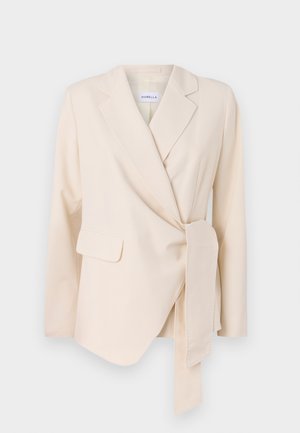 Blazer beige sur mesure avec manches longues, design enveloppant, ceinture à la taille et deux poches avant. Texture lisse et forme structurée.