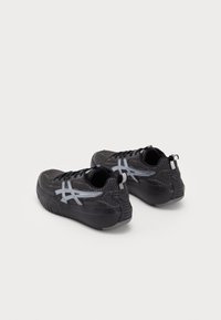 Black athletic shoes with a textured upper, gray accents, and a raised sole. Features a smooth heel and traditional lace closure.