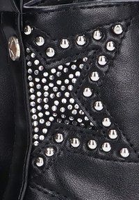 Cuero negro con acentos plateados con tachuelas y pedrería en forma de estrella, que presenta un acabado texturizado y costuras detalladas.