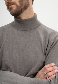 Grauer Rollkragenpullover aus weichem Strickmaterial, mit geripptem Kragen und nahtlosem Design, körpernah an Schultern und Armen.