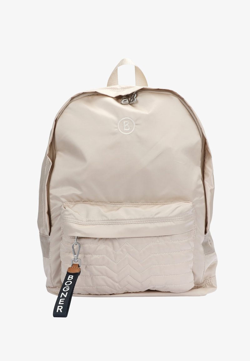 Sac à dos en nylon beige avec une poche avant matelassée, des tirettes de fermeture éclair argentées, un logo circulaire et un porte-clés noir portant l'inscription « BOGNER ».