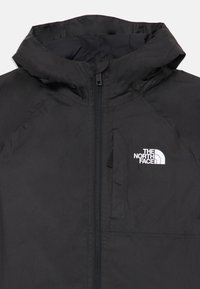 Veste à capuche noire avec une fermeture éclair sur le devant et une poche poitrine. Le tissu est lisse avec une finition mate ; logo blanc sur le côté gauche.