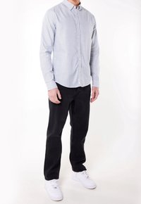 Koszula na guziki w jasnoniebieskie i białe paski, długie rękawy, zestawiona z czarnymi dżinsami i białymi trampkami. Prosty kołnierzyk i subtelny wzór.