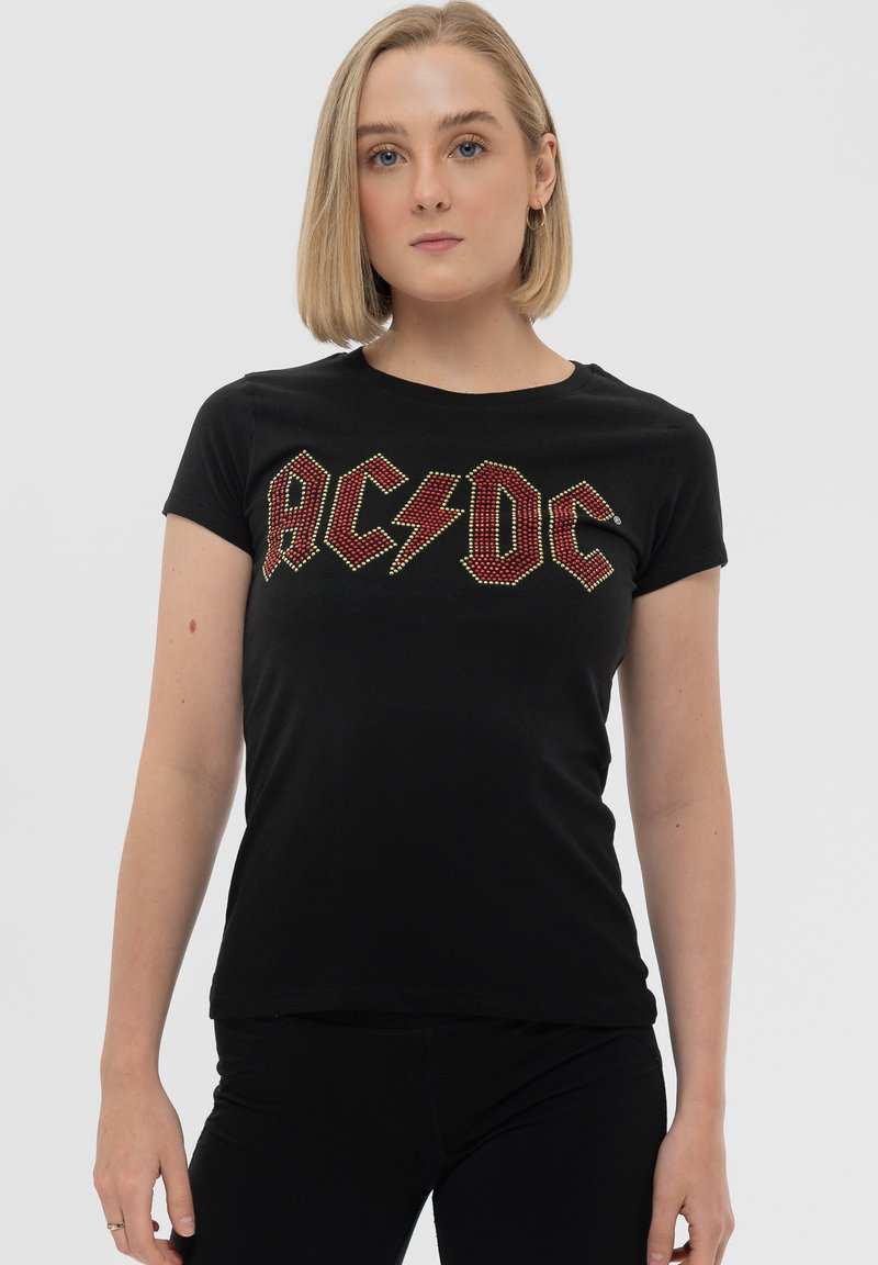 Black cotton t-shirt with short sleeves featuring red and yellow rhinestone AC/DC logo and lightning bolt design at the center.