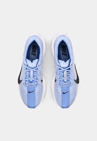 Baskets sportives bleu clair avec une tige en maille, des accents noirs et des semelles blanches. Caractéristiques d'un design à lacets et d'une étiquette de marque sur la languette.