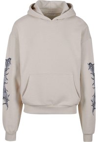 Beige hoodie lavet af bomuld, med en frontlomme, snøre i hætten og indviklede sorte grafikdesigns langs ærmerne.