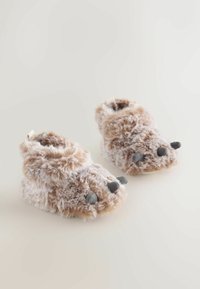 Puchate brązowe buciki z akcentami przypominającymi pazury. Miękka, pluszowa tekstura. Zaokrąglony kształt z trzema szarymi końcówkami na palcach. Brak widocznych elementów metalowych.