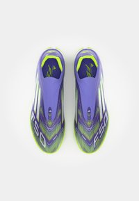 Lilla og neongrønne atletiske sko med slip-on design, der har teksturerede mønstre og en strømlinet form. Udsmykket med logo.