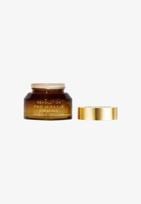 Bärnstensfärgad glasburk med nattkräm, försedd med ett guldfärgat lock. Texten på burken lyder "Revolution Pro Miracle Firming Night Cream."