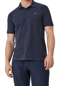 Granatowa koszulka polo z bawełny, o miękkiej teksturze, z zapięciem na dwa guziki i małym pomarańczowym logo po lewej stronie klatki piersiowej. Krótkie rękawy i klasyczny krój.