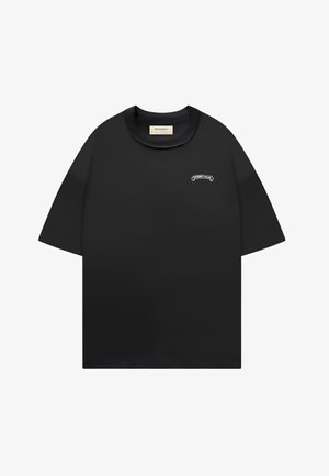 T-shirt noir manches courtes en maille gaufrée avec col rond et petit logo blanc "RETERNITY ATELIER" sur le haut gauche de la poitrine.
