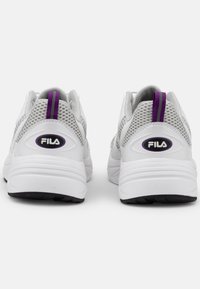 White FILA sneakers with mesh panels, purple accents, and a textured rubber sole. Features a heel tab for easy wear.