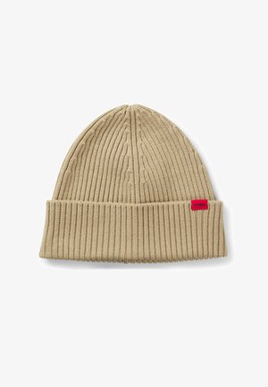 Beige gestrickte Mütze mit einer gerippten Struktur und einem umgeschlagenen Bund. Mit einem kleinen roten Markenzeichen mit der Aufschrift "HUGO".