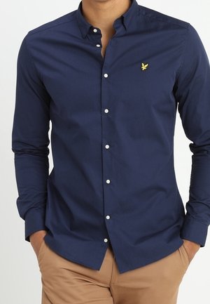 Marineblauwe longsleeve shirt van katoen. Heeft een button-down kraag, witte knopen en een klein geel arendlogo op de borst.