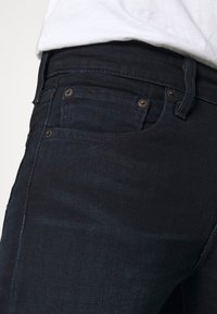 Mörka jeans i denim har en smal passform, med subtil blekning, standardfickor och koppardetaljer på framsidan.