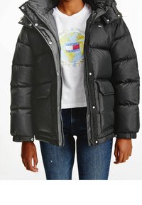 Svart pufferjacka med glänsande yta, dragkedja framtill, bröstficka och huva, bärs över en vit T-shirt med globdesign.