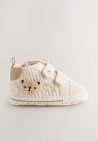 Crèmekleurige baby schoen van ribfluweel met twee klittenbandsluitingen, teddyberen patch en een hielstuk van beige suède.