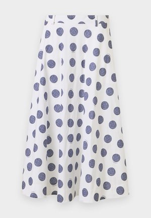 En knælængde, hvid nederdel med en udvidet design, der har store marineblå polkaprikker. Den har en glat tekstur og plisserede detaljer.