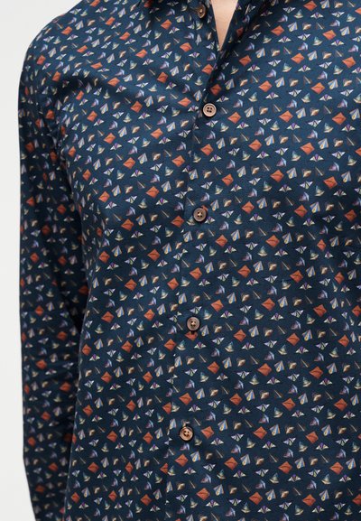 Μπουφάν σε ναυτικό μπλε με σχέδιο από μικρά πορτοκαλί, μοβ και πράσινα γεωμετρικά σχήματα και καφέ κουμπιά μπροστά.