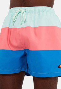 Bañadores coloridos con rayas horizontales en azul claro, rosa y azul oscuro, con cinturilla ajustable y logotipo en el lado inferior.