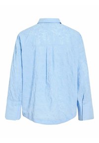 Camisa azul clara de manga larga con sutiles patrones florales abstractos en relieve y puños con botones, mostrada desde atrás.