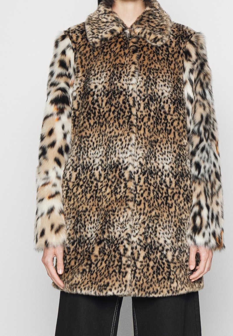 Manteau mi-long ajusté en fausse fourrure à imprimé mixte léopard et guépard, porté par une personne debout devant un fond clair uni.