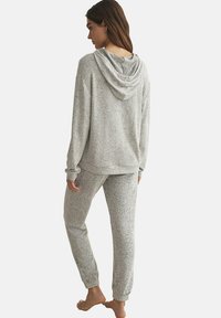 Ensemble de sweat à capuche et de pantalon de survêtement en tissu doux et texturé. Comprend une capuche, des manches longues et des poignets élastiques pour plus de confort.