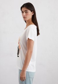 Witte katoenen t-shirt met korte mouwen, voorzien van een kleurrijke grafische print aan de voorkant. Eenvoudige ronde halslijn, comfortabele pasvorm en zachte textuur.