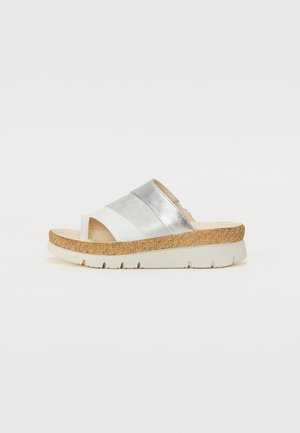 White slide sandal with silver accents, cork sole, and textured upper. Features two wide straps and a slight wedge heel.