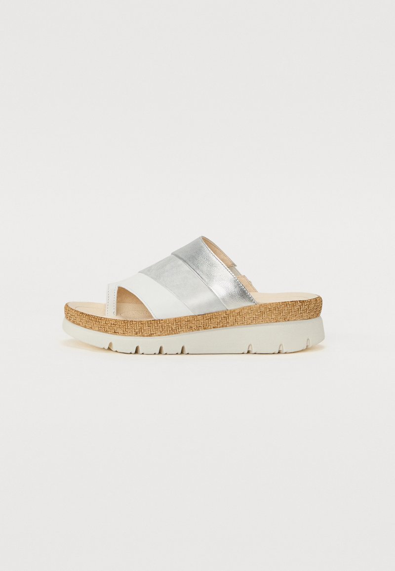 White slide sandal with silver accents, cork sole, and textured upper. Features two wide straps and a slight wedge heel.